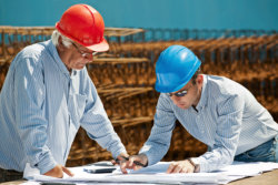 Young engineer shows a senior foreman the next steps in a construction project.